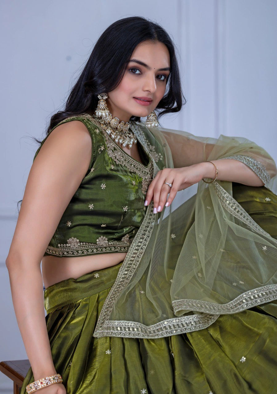 Woman wearing a green traditional outfit with jewelry against a white background